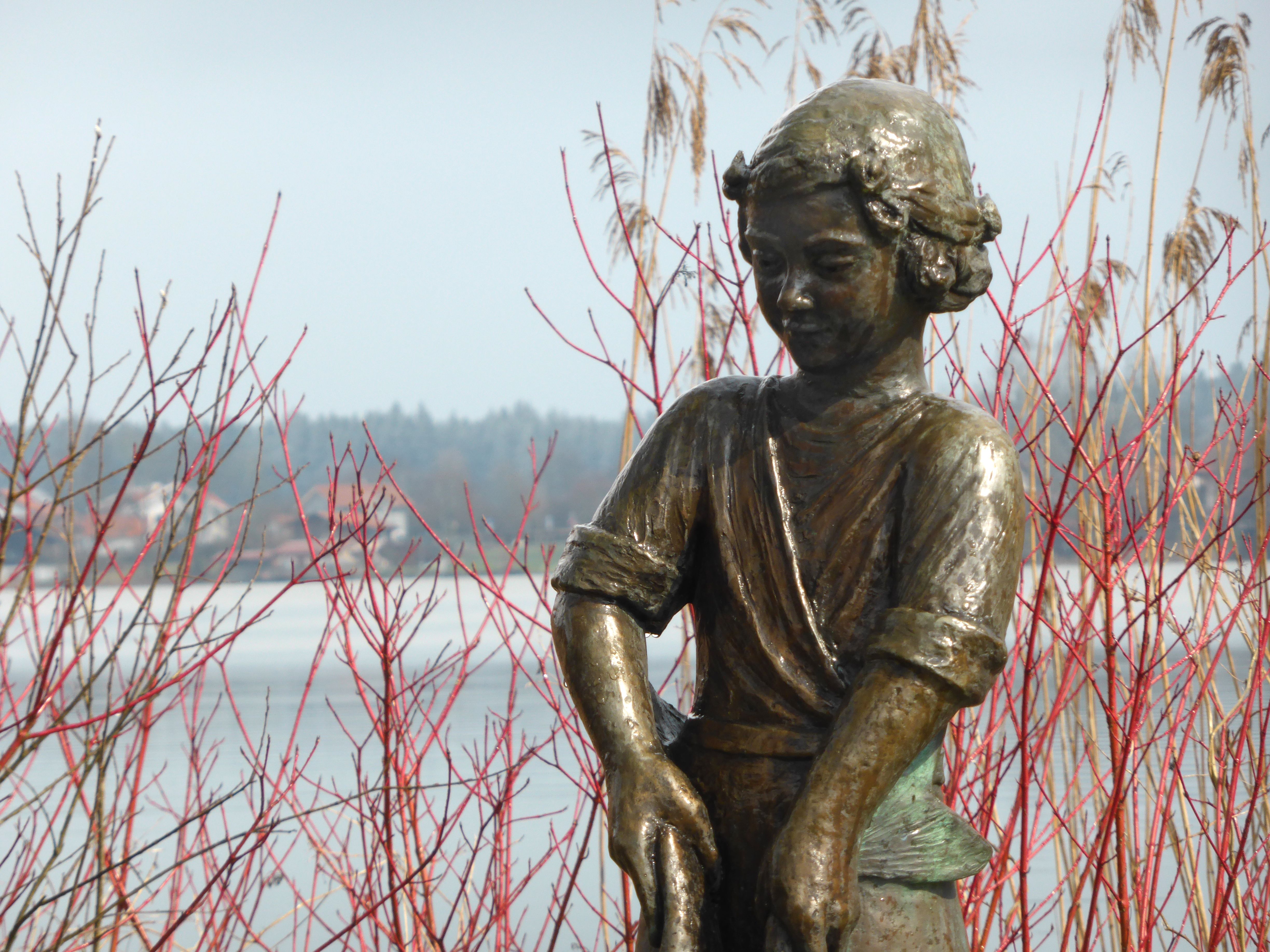 Eine Bronzefigur zeigt einen Jungen, der am Ufer des Seeoner Sees steht.